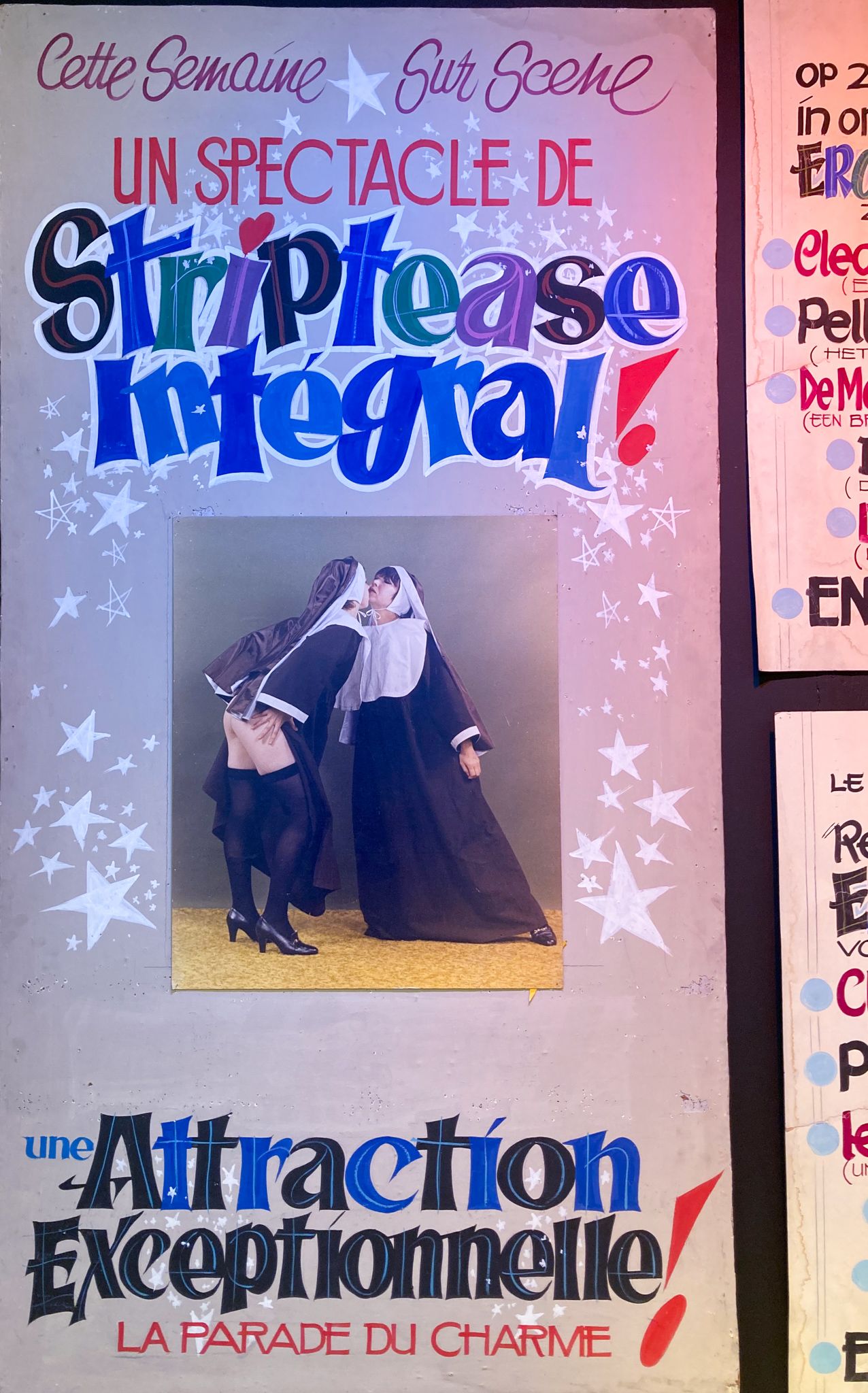 Une affiche annonçant "Un spectacle de striptease intégral". On y distingue deux nônes, l'une les fesses à l'air.
